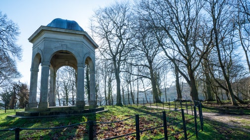 View of temple with bare trees and bright blue sky at Sheringham Park, Norfolk.